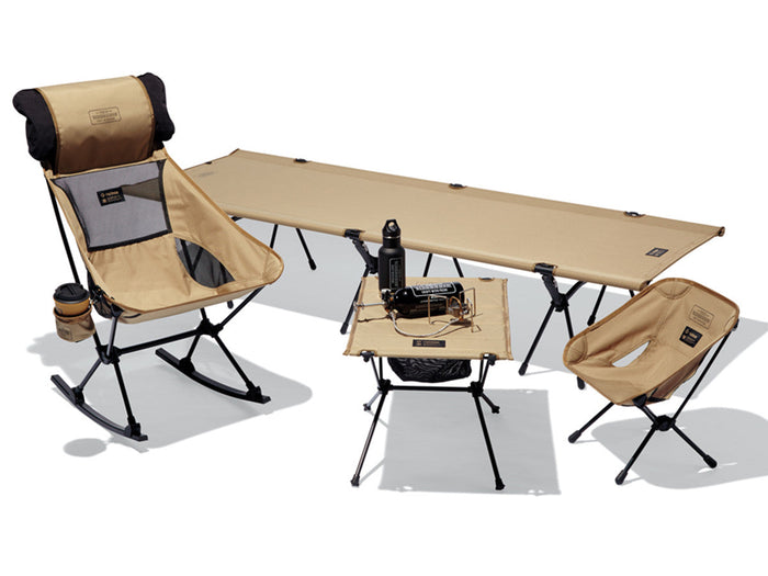 Helinox tan camping gear set with rocking chair, camp chair, table, and cot on a white background