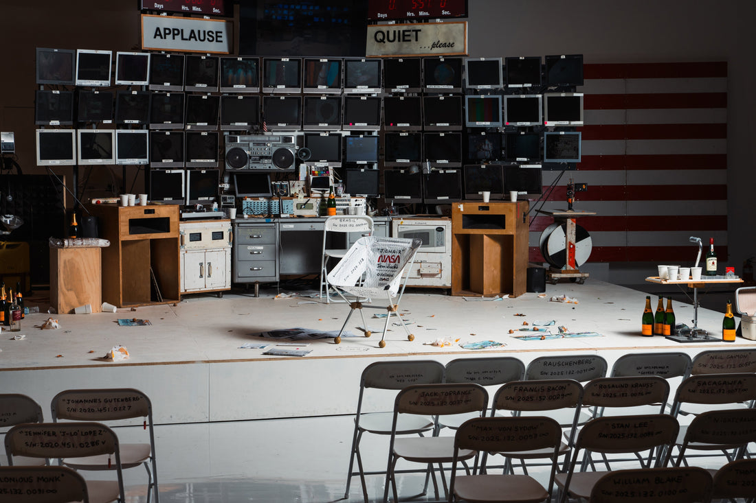 A stage setup with rows of chairs facing a wall of television monitors.