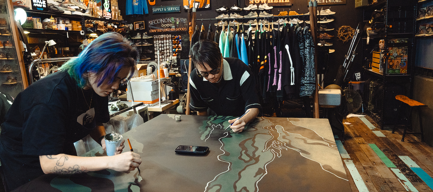 Two individuals painting a large canvas inside a retail store.
