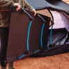Person putting a camp cot into a tent