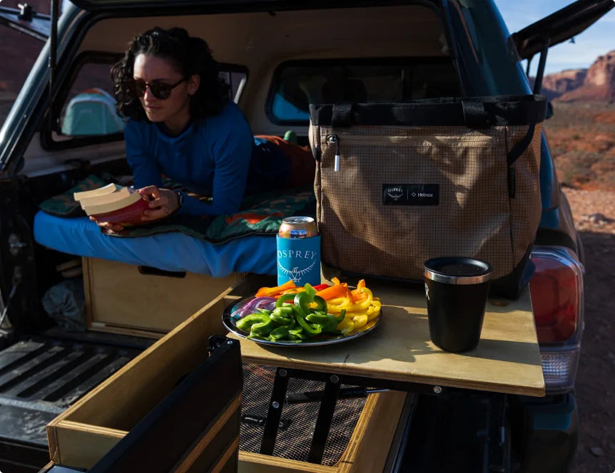 Camper relaxing with an Osprey cooler and snacks